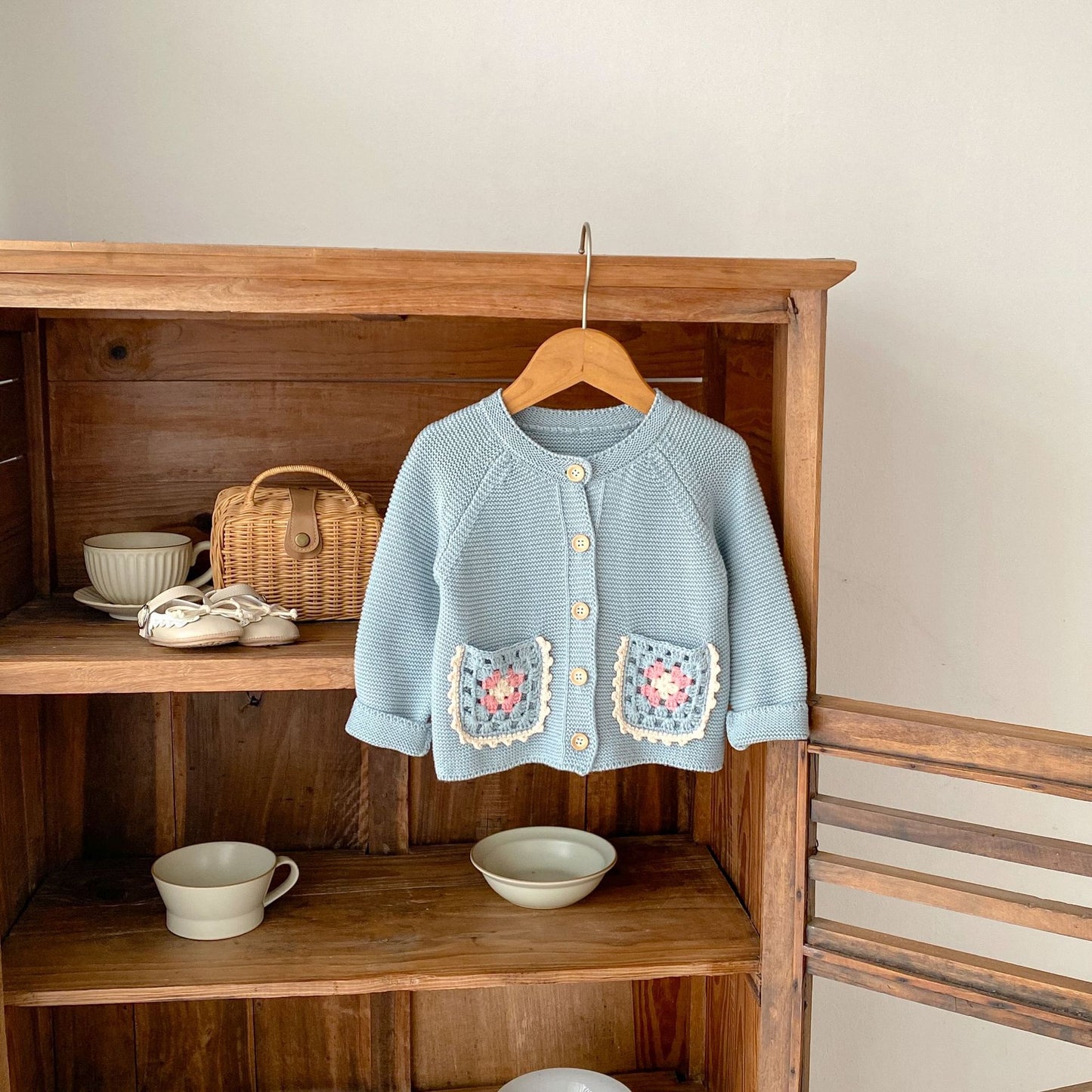 Petal Acorn Cardigan on wooden hanger, shelf styled